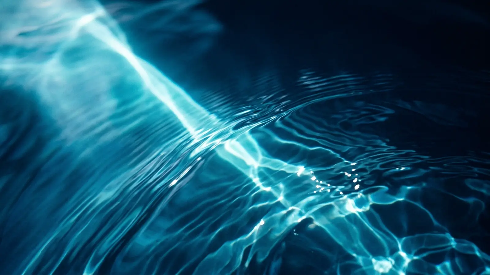 Abstract macro view of clear water with subtle ripples and refracted light beam